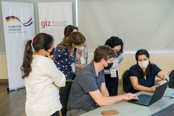 Employees of the ‘Laboratorio Central de Salud Publica’ sit in front of a laptop, receiving training on the bioinformatic analysis of sequencing data. © GIZ/Arne Auste