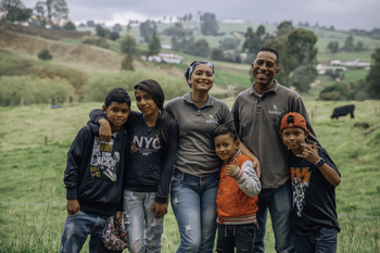 State representatives standing together with a refugee family. A girl shows an identity document to the camera.