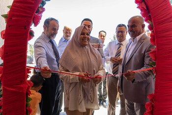 A woman cuts a cord at the opening of a women's centre.