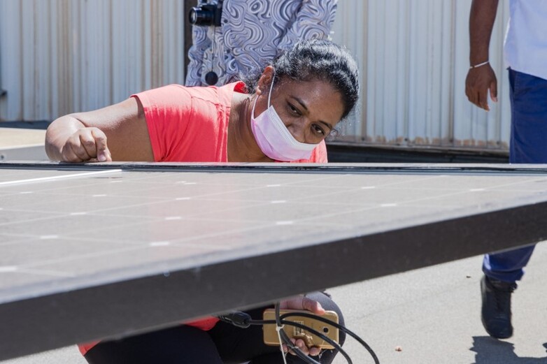 A woman inspecting a solar panel.