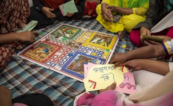 Several seamstresses in a women’s café playing a game that explains their rights.