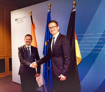 BMDV State Secretary Stefan Schnorr and his Indian colleague Alkesh Sharma shaking hands in front of a wall and flags at the Digital Dialogue.
