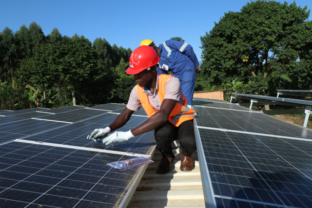 DKTI Solar technicians: Solar technicians install panels on top of a mini grid remote unit  in Lamwo District, Northern Uganda 
