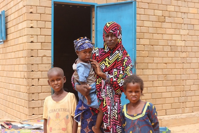A refugee family in front of their new house constructed by the Global Programme in Niger. © UNHCR Niger