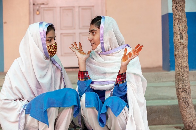 Dos alumnas pakistaníes charlan sentadas en una escalera. Derechos de autor: GIZ / Abdul Wahid.