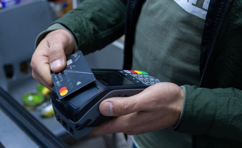 An individual holding a credit card, getting ready to make a payment.
