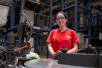 An employee standing in the production hall of a metal company.