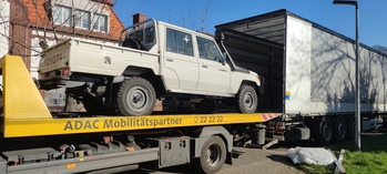 A pick-up truck being loaded into a lorry. 