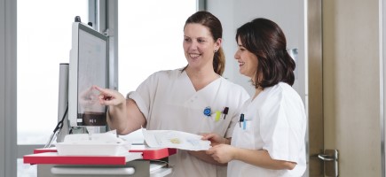 Two nurses look at a screen.