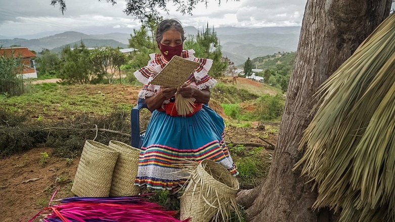 A woman making baskets from palm leaves. Copyright: GIZ