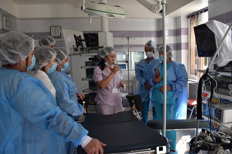 Medical staff in protective clothing holding a discussion while gathering around a surgical table. Copyright: GIZ
