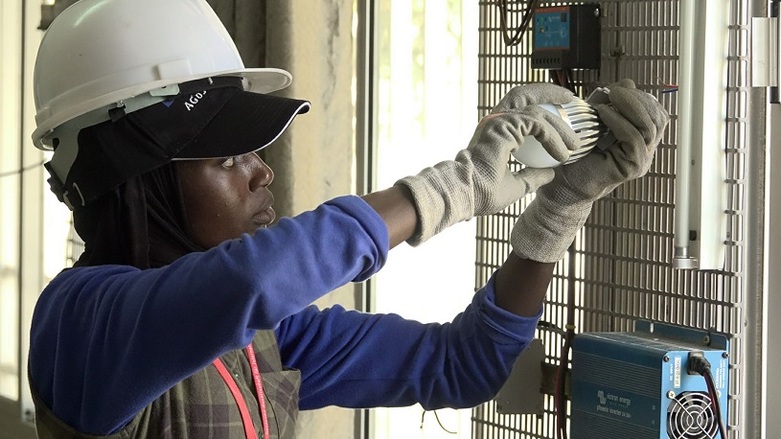 Une technicienne portant un casque et des gants de protection installe un système photovoltaïque. Droits d’auteur : GIZ