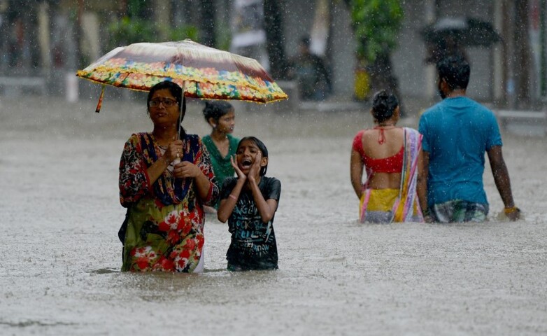People in India walk through waist high water in the streets