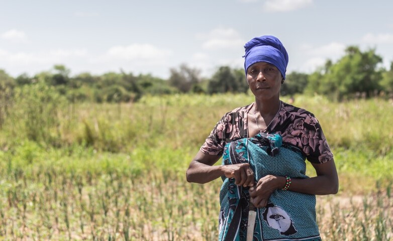 A farmer standing in a field, holding a knife in her hand