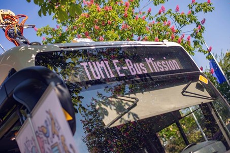 Close-up of an electric bus with ‘TUMI E-Bus Mission’ written on the digital display. © TUMI