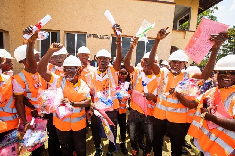 Construction workers in safety vests and helmets cheer with certificates in their hands. Copyright: John Healey
