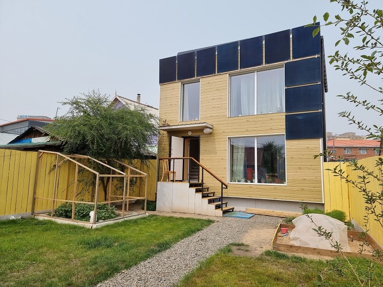 A small, modern residential building with photovoltaic solar panels on its façade.