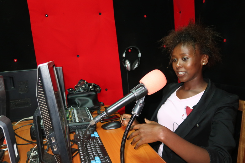 A woman sits in front of the microphone in a radio station.