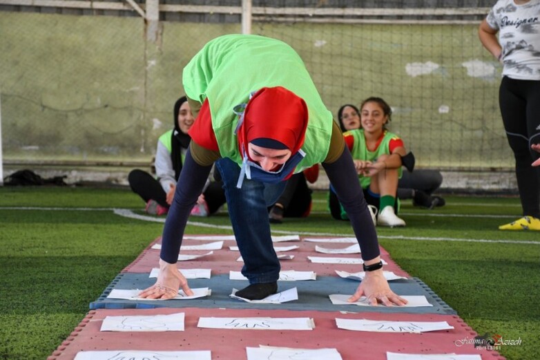 A girl does a sports exercise on a football field