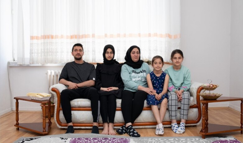 A family photo showing a mother with four children on a sofa. 