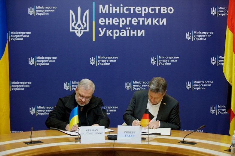 Two politicians from Ukraine and Germany sign papers together.