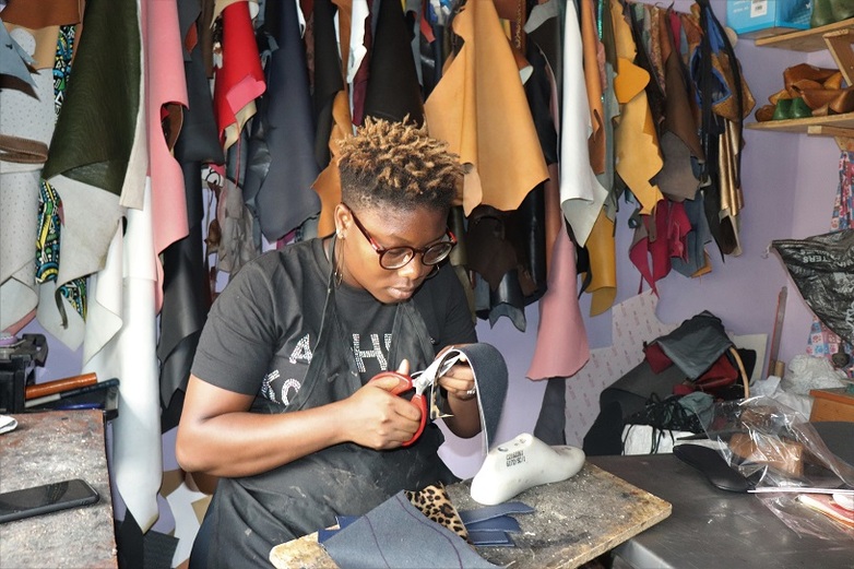 A woman cuts pieces of leather. Copyright: Oladipo Olurishe / GIZ