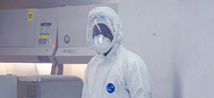 A man in protective clothing in a laboratory.