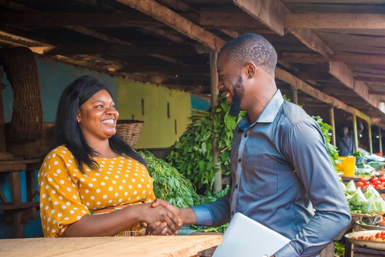 Afrikanische*r Geschäftsmann und Geschäftsfrau schütteln Hände auf einem Markt” Copyright: I_am_zews/Shutterstock.com