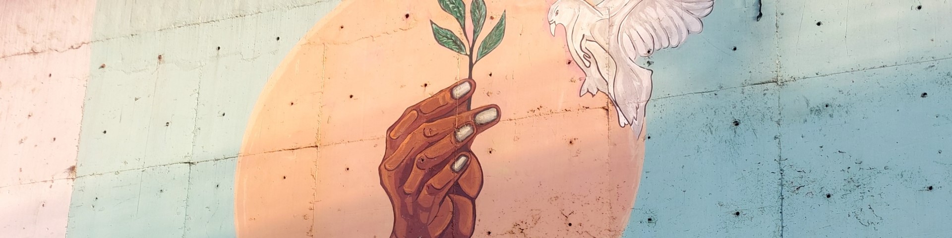 A painting on a wall shows a peace dove and a hand holding an olive branch.