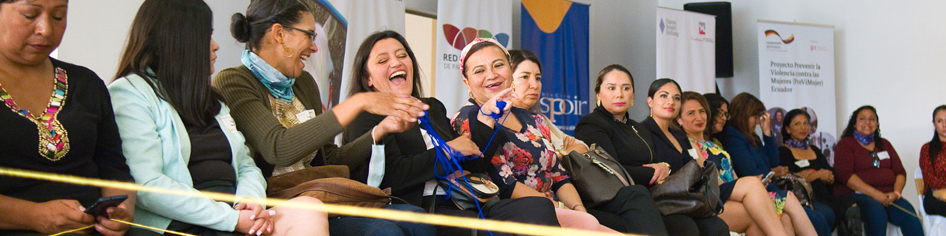 Mujeres riendo sentadas juntas en una sala de conferencias. © PreViMujer/GIZ (2022)