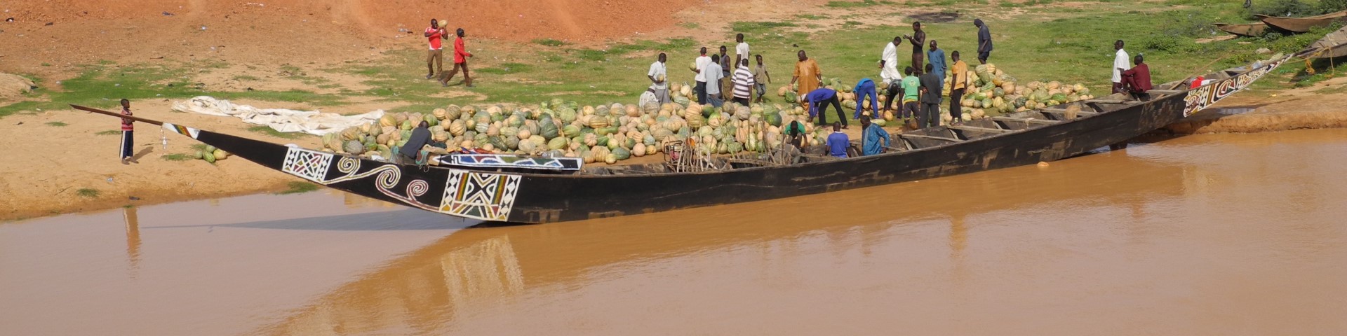 People unload a wooden ship with pumpkins in Niger.
