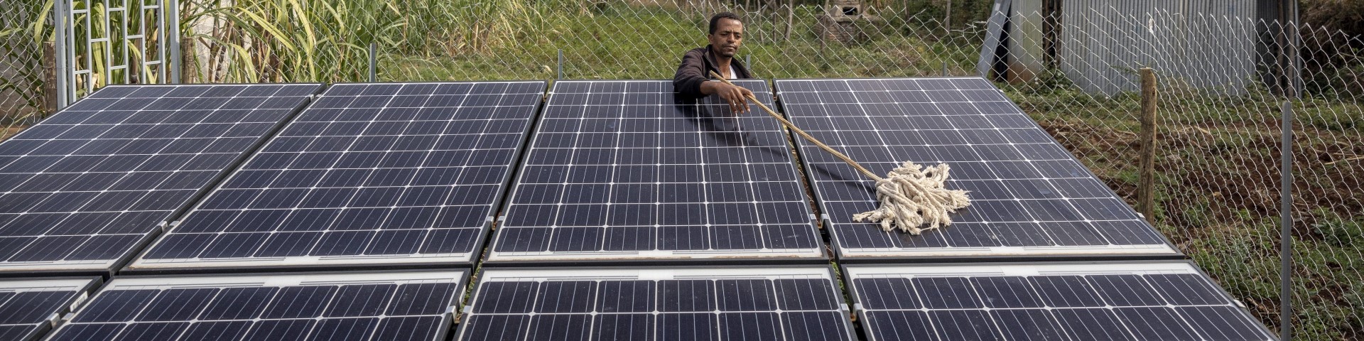 A man removes dust from solar panels at a health centre in Ethiopia. © GIZ
