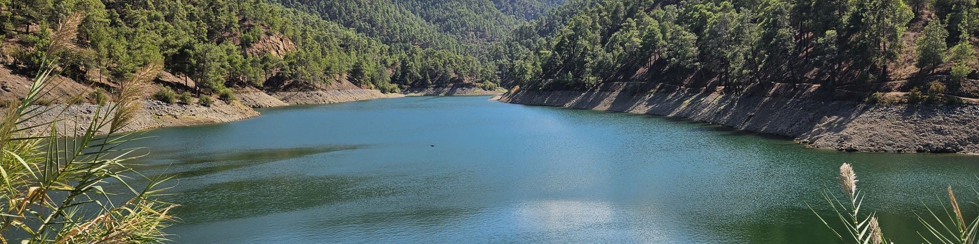 A reservoir located in a green, mountainous landscape