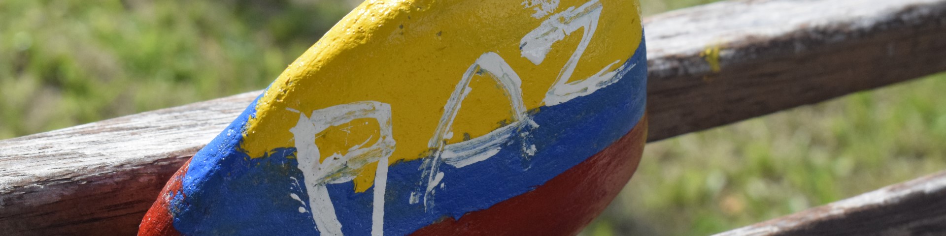 A stone painted with the word ‘PAZ’ lies against the back of a wooden bench.