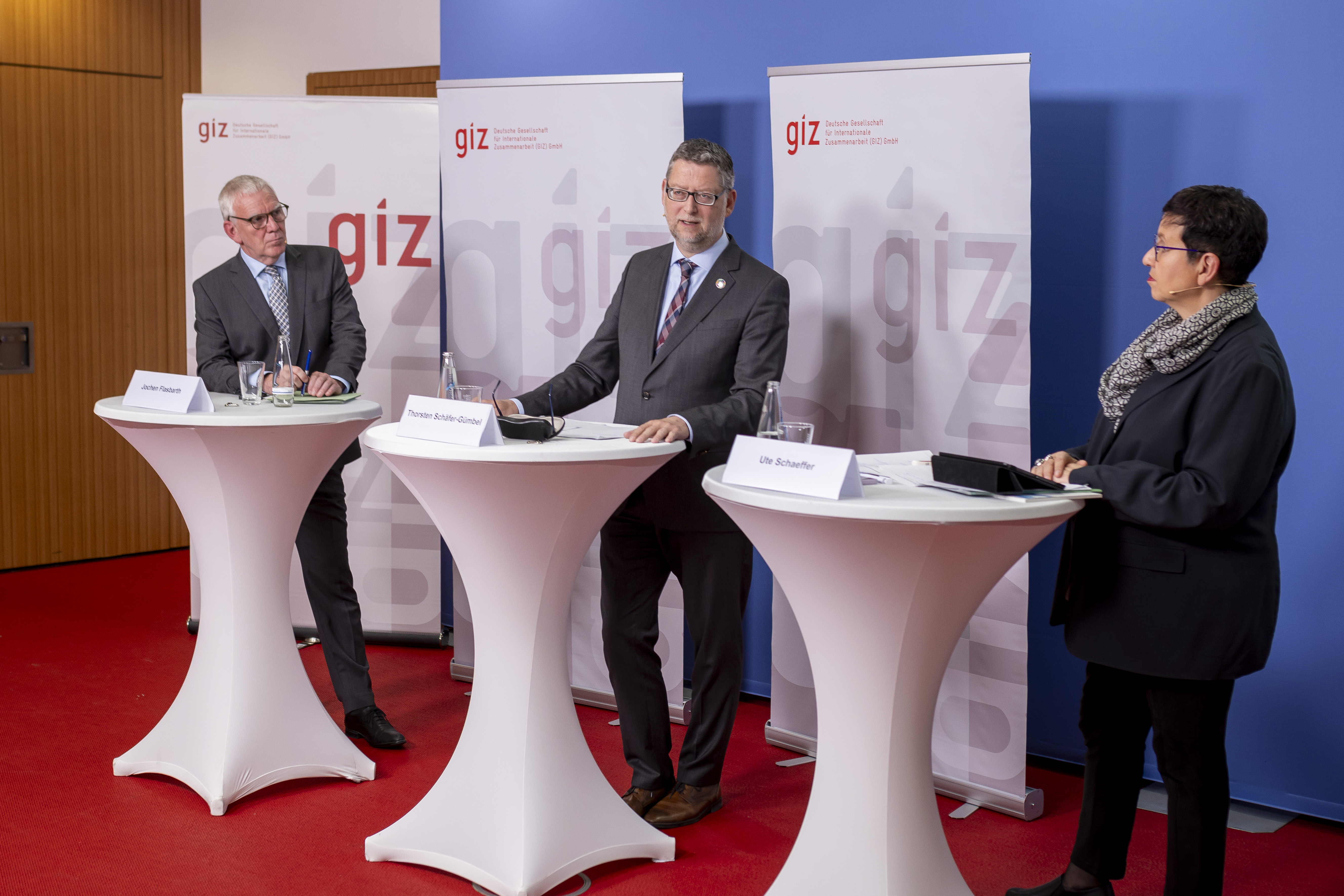 Jochen Flasbarth, Thorsten Schäfer-Gümbel and Ute Schaeffer at speaker's desks in front of GIZ banners.