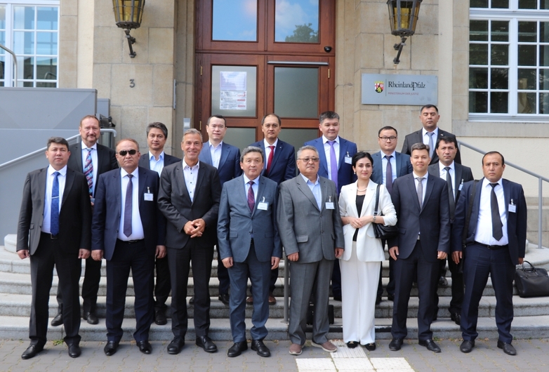 A group photo with many men and one woman in suits standing in front of steps leading into a building in Koblenz.