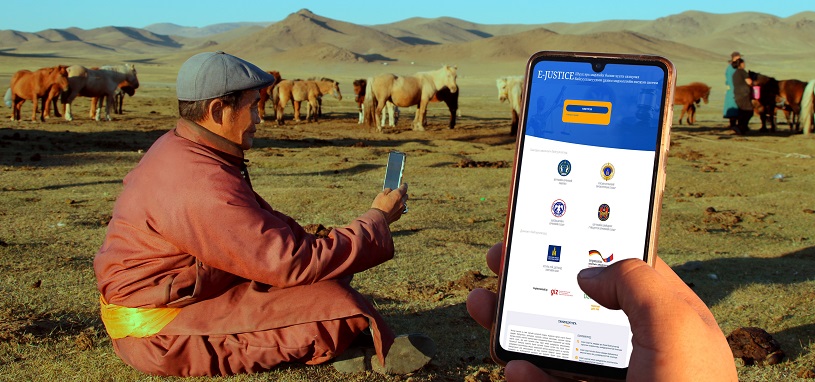 A man sitting in the steppe holds a smart phone.