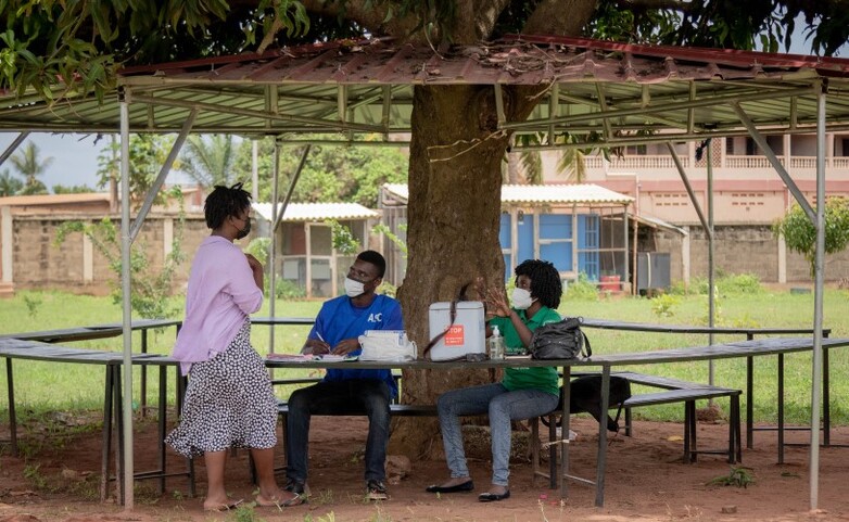 Three people wearing masks have a discussion.