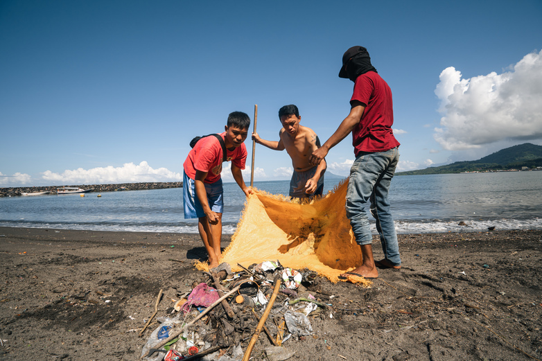 People collecting plastic waste on a beach in Manado city.