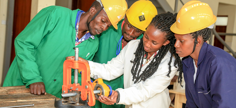 Two men and two women from Kenya at a workbench.