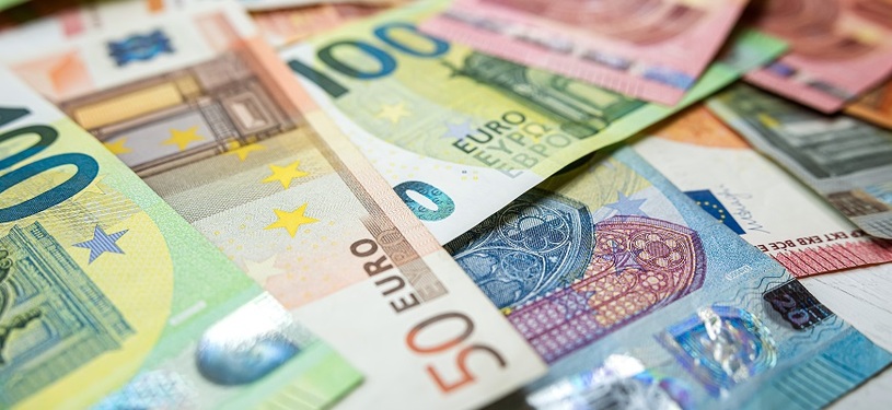Various Euro banknotes lie scattered on a table.