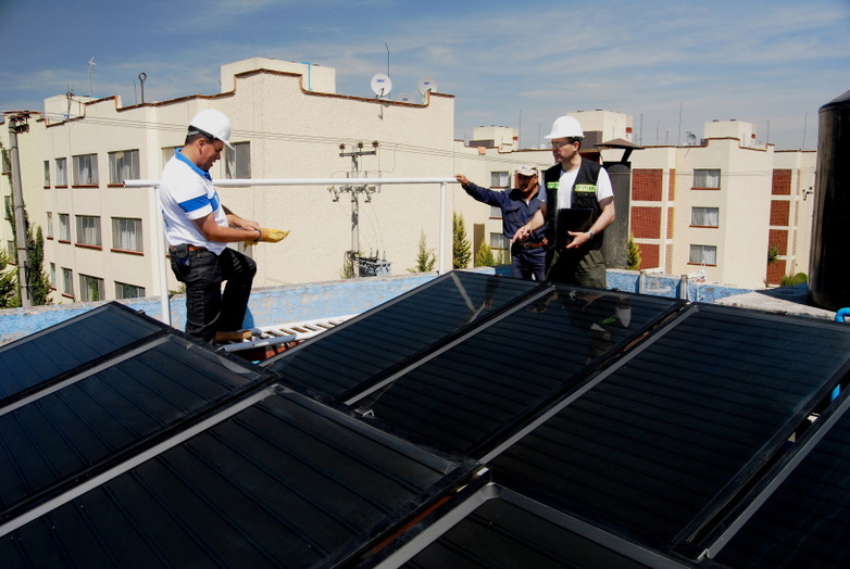 Technicians installing solar panels on the roof of a building