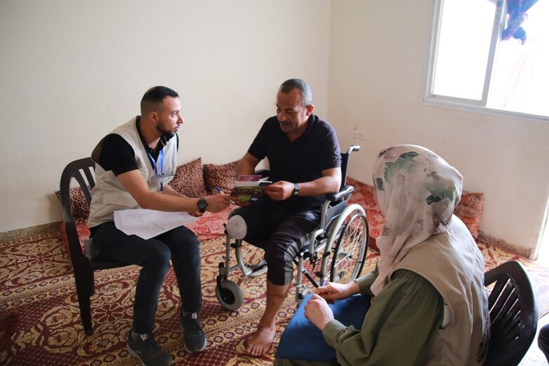 An employee from a mobile clinic performs a home visit to offer psychosocial support to a person with a disability. © GIZ / GCMHP 