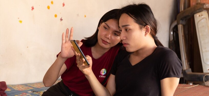 Two young women are looking at the screen of a smart phone.
