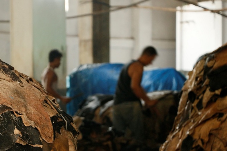 Two men work in a tannery between stacks of hides. Copyright: GIZ/Victoria Hohenhausen.