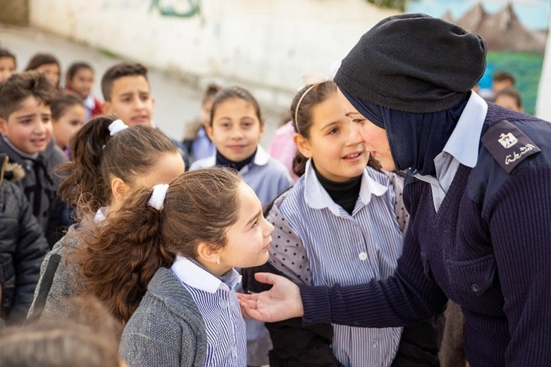 A police officer with a head scarf talks to a young girl.