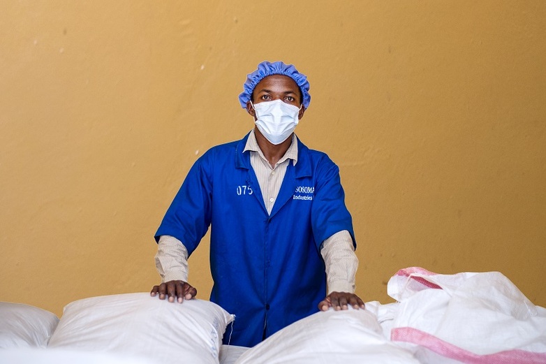 Employee standing behind several packets of corn flour. Copyright: Emmanuel Hitimana