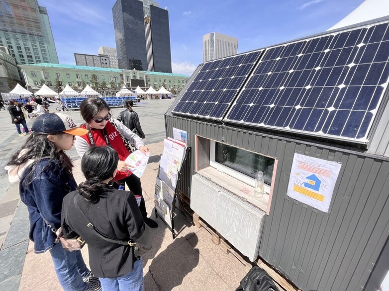On Europe Day, a person provides information about photovoltaic solar panels on the roofs of residential buildings.