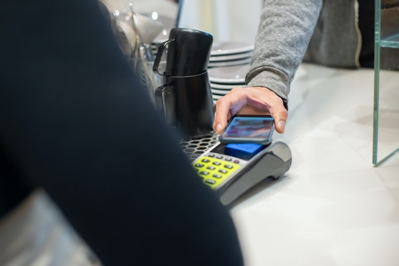 Someone pays contactlessly with a smartphone in a café. Copyright: GIZ