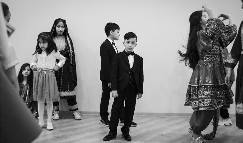 A black-and-white photo showing a group of children dancing and playing. 